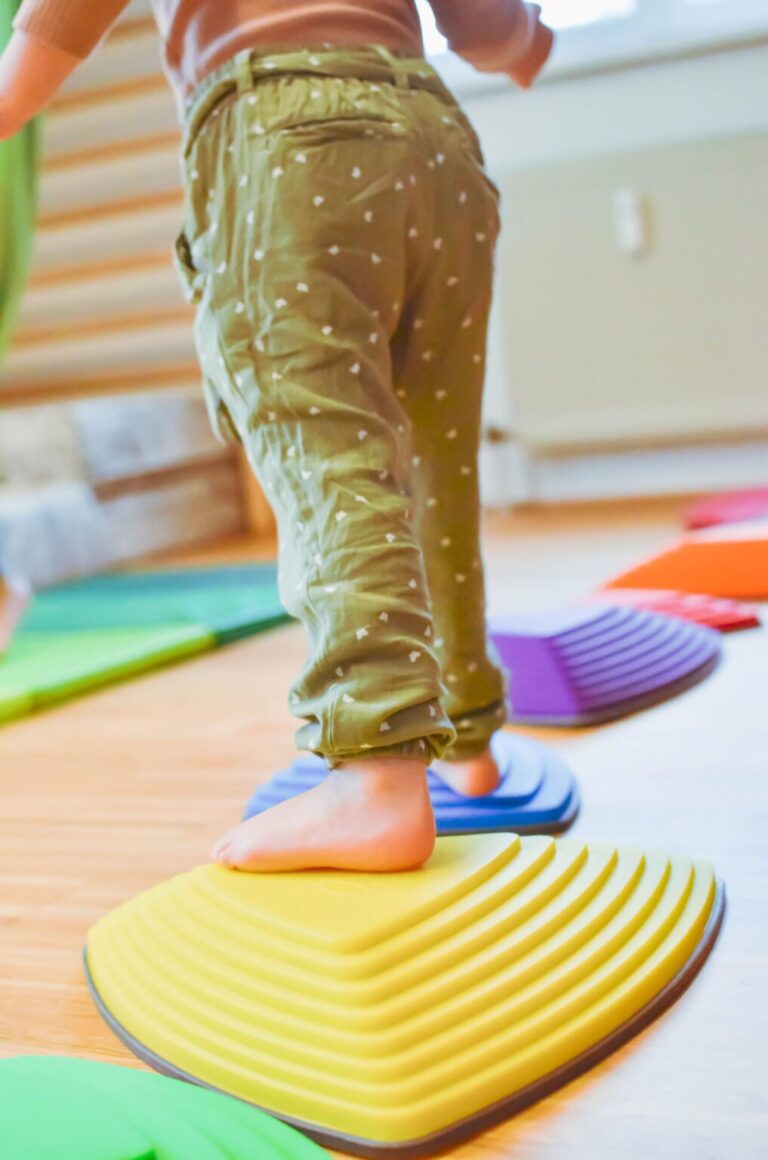 Kinderfüße auf bunten Balancier-Steinen